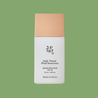 Olivine Beauty Daily Tinted Fluid Sunscreen SPF 40 bottle with beige cap and matte white packaging on green background.