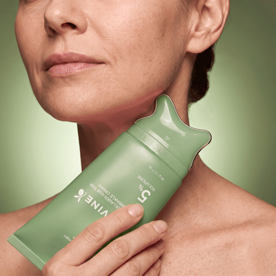 Woman gliding the green Olivine Beauty PDRN Collagen Gua Sha Neck Wrinkle Cream applicator along her neck