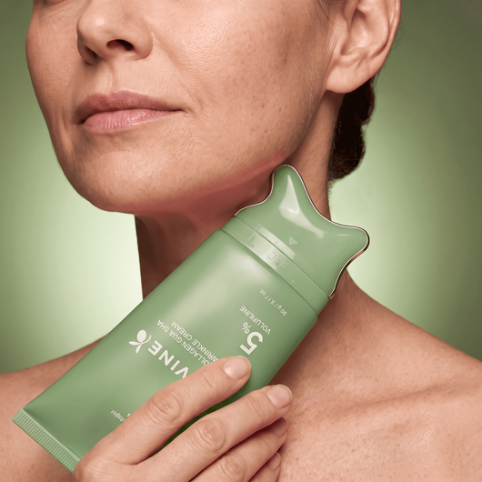 Woman gliding the green Olivine Beauty PDRN Collagen Gua Sha Neck Wrinkle Cream applicator along her neck
