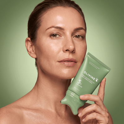 Woman holding the green Olivine Beauty PDRN Collagen Gua Sha Neck Wrinkle Cream tube