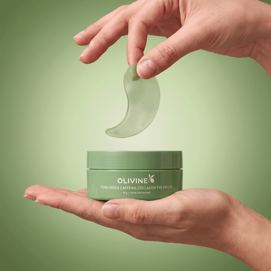 Hand holding a single green Olivine Beauty PDRN Green Caffeine Collagen Eye Patch hydrogel patch above the open jar