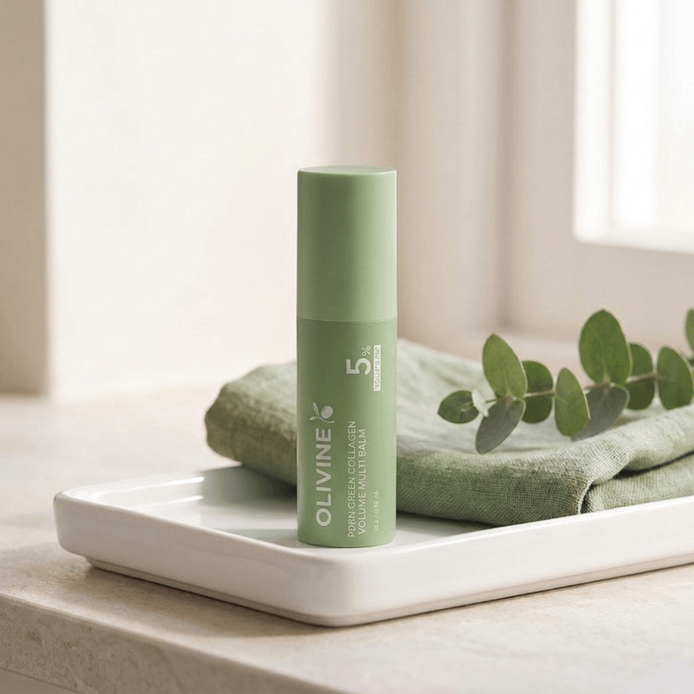 Olivine Beauty PDRN Green Collagen Volume Multi Balm stick on a tray with eucalyptus