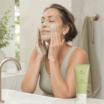 Olivine Matcha Pack Cleanser held by a woman with glowing skin